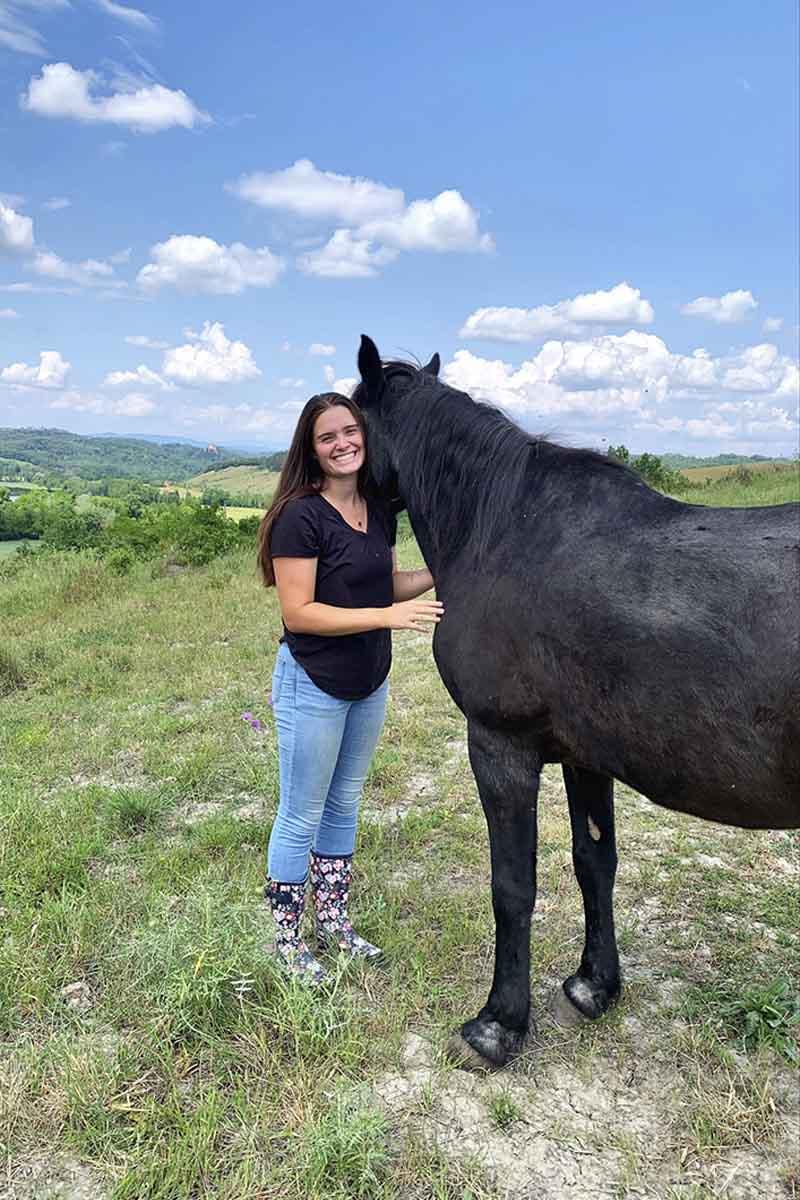 牧场上，一位妇女站在一匹马旁边.